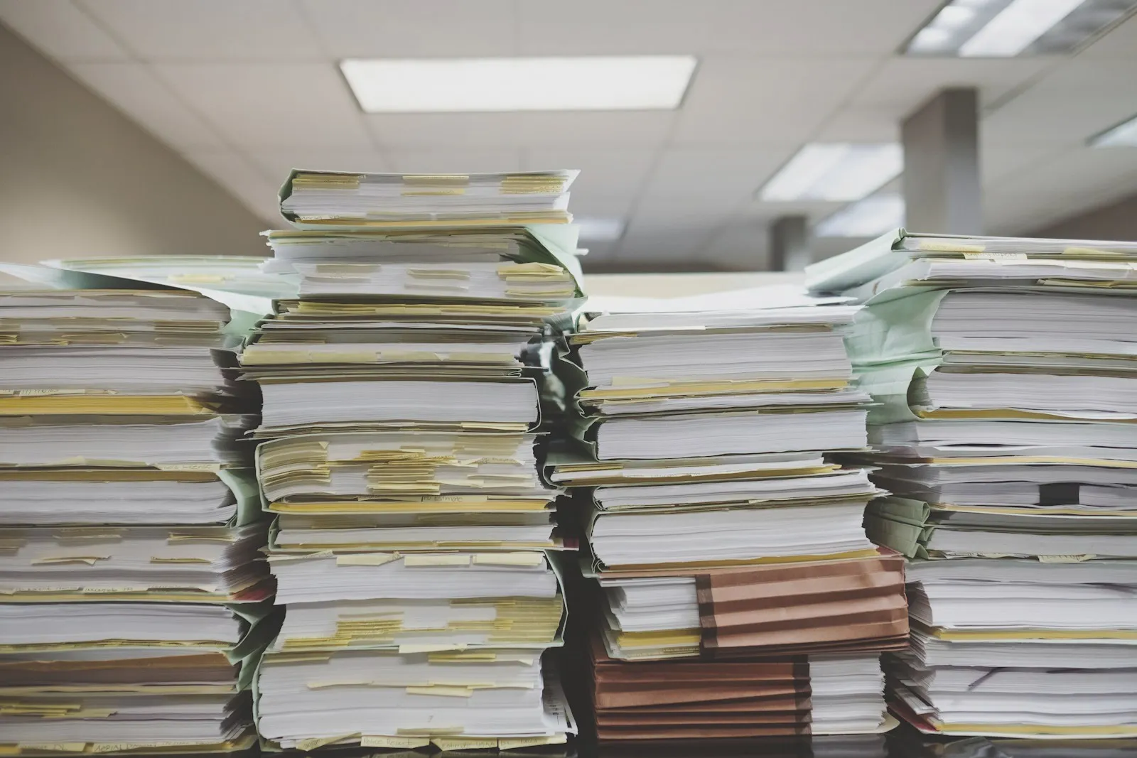 Tall stacks of paper documents and file folders in an office