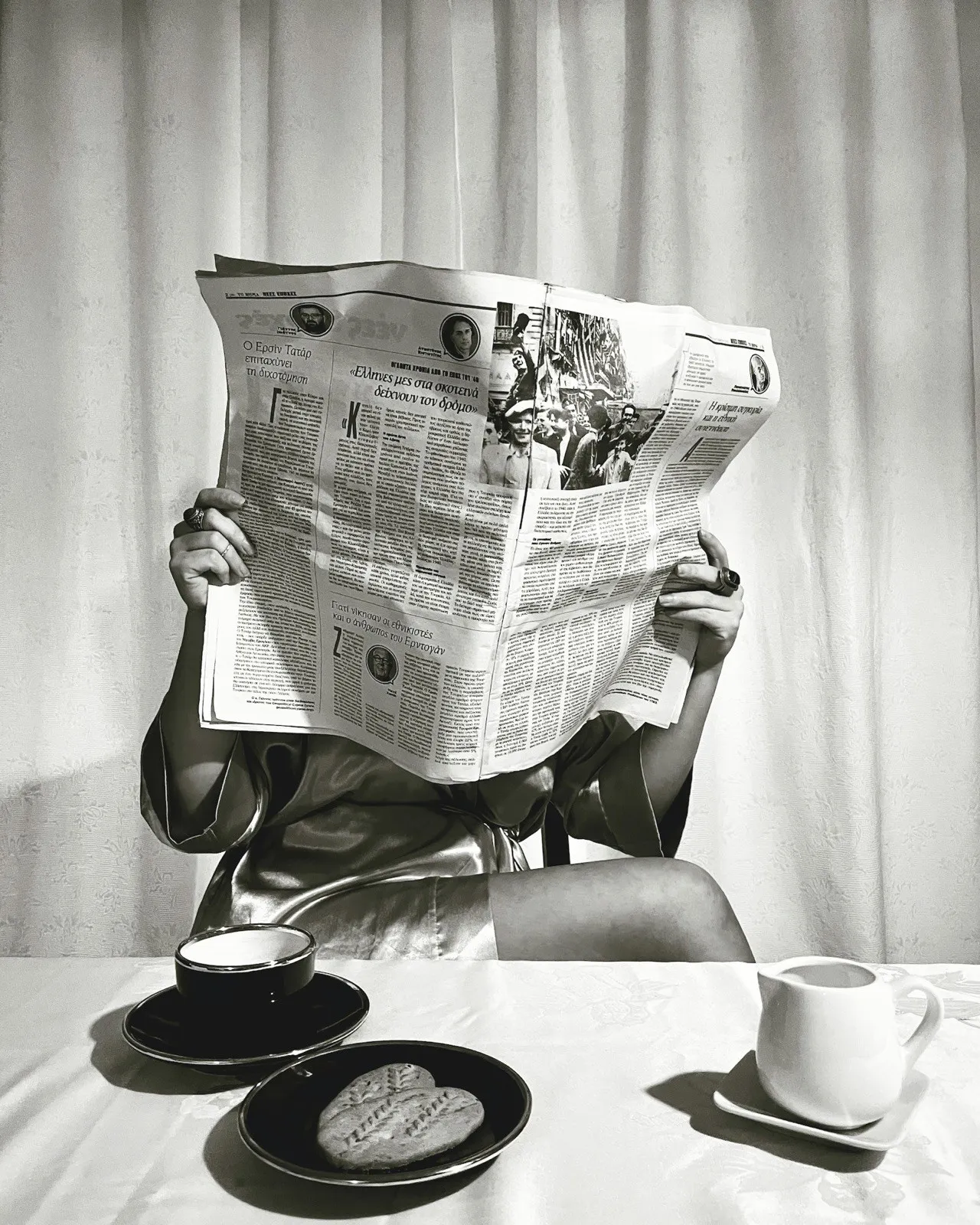 Someone reading a broadsheet newspaper held open in front of them